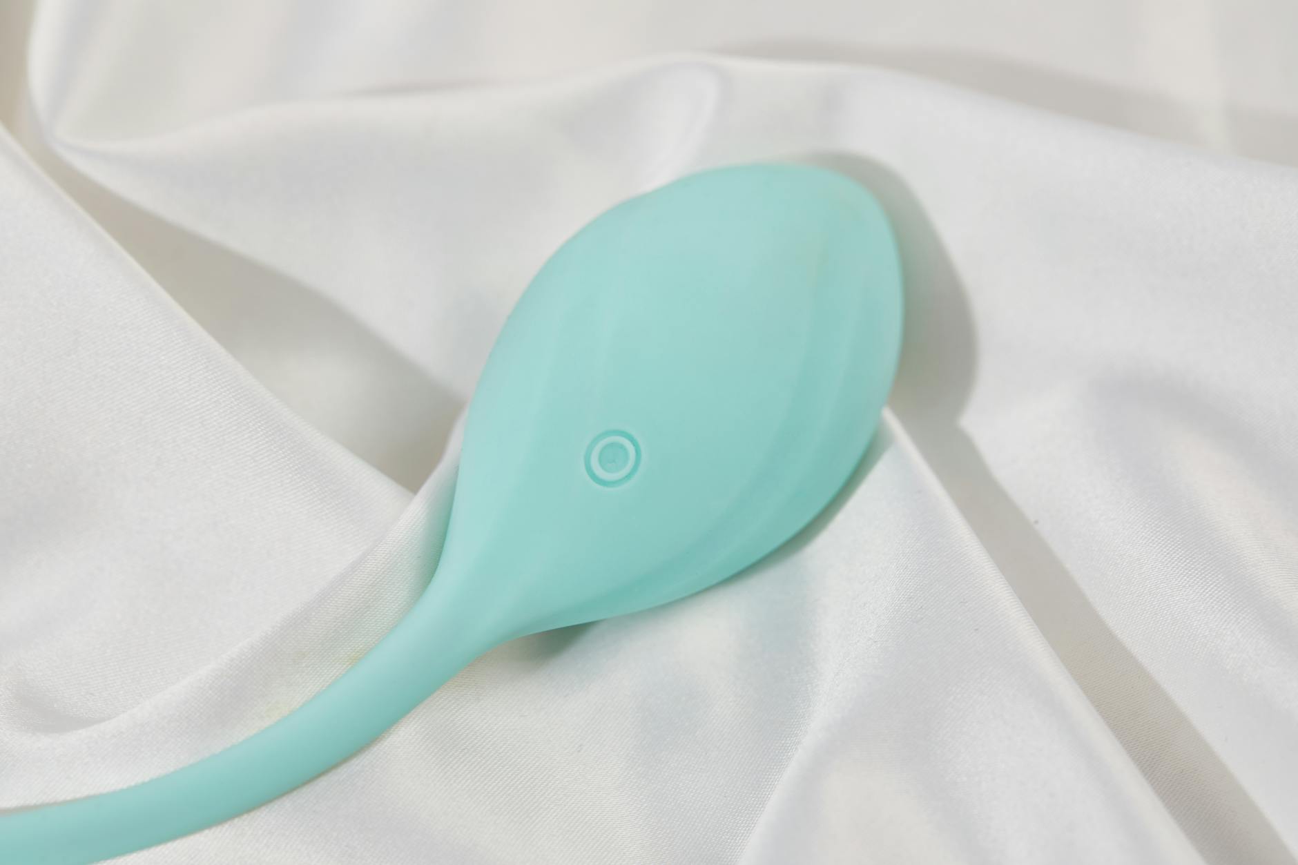 A teal silicone lemon vibrator on soft white fabric, symbolizing safe postpartum intimacy