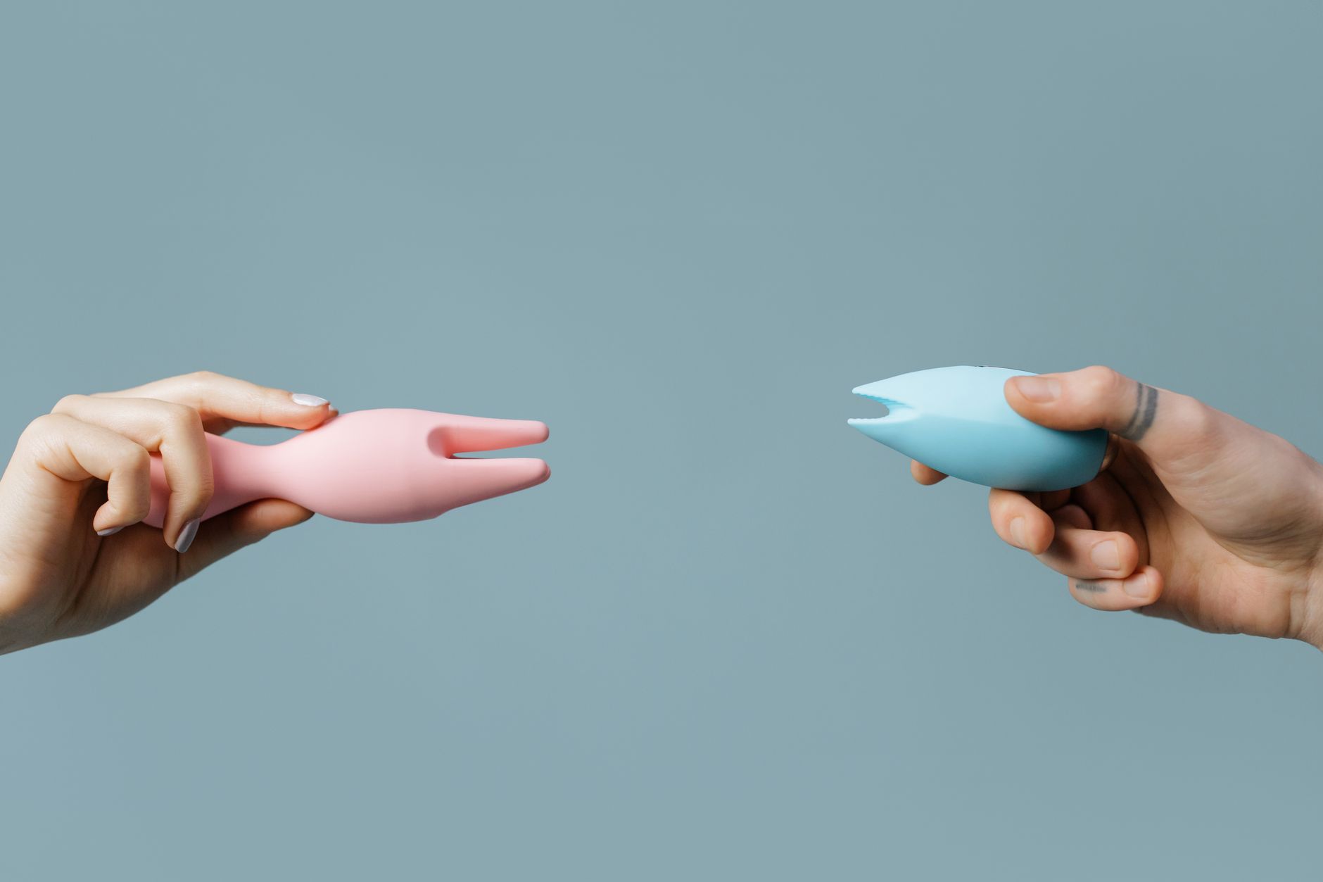 Two hands holding vibrators against a soft background, representing personalized pleasure exploration