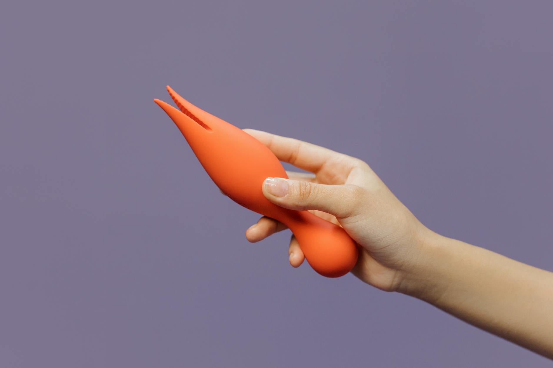 Close-up of a hand holding a vibrator against a minimalist purple backdrop, representing modern solutions for couples