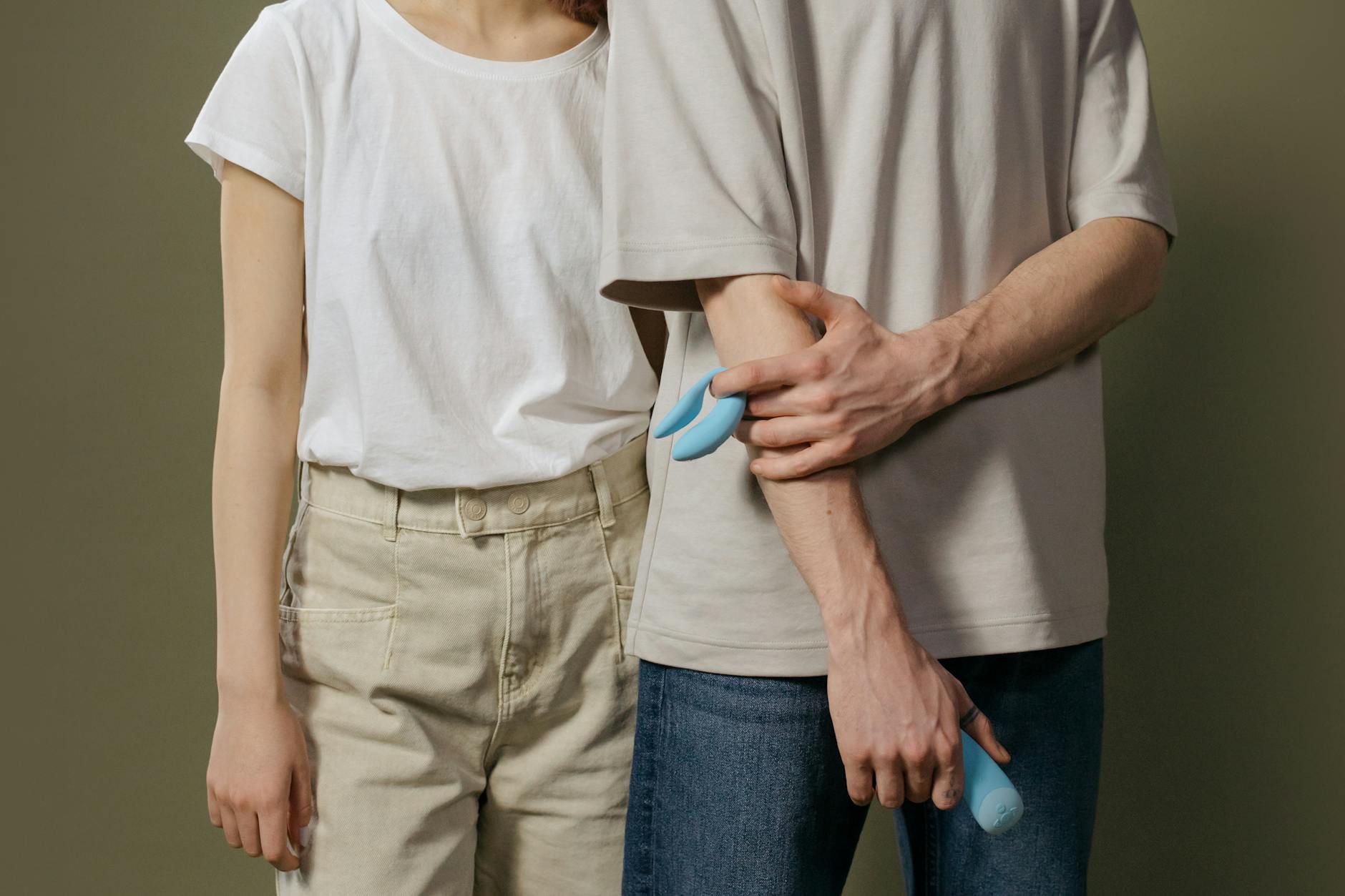 Close-up of hands holding a blue personal massager against a knitted sweater.
