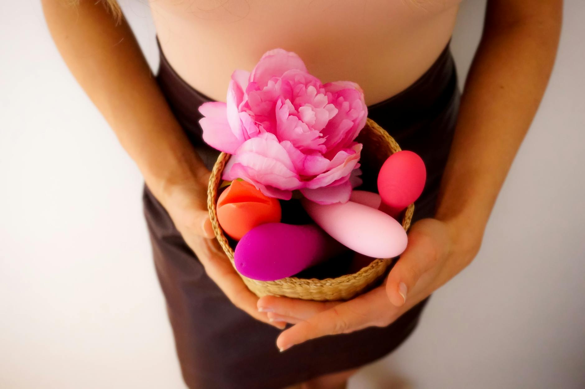 Close-up of hands holding a sleek vibrator against a purple background