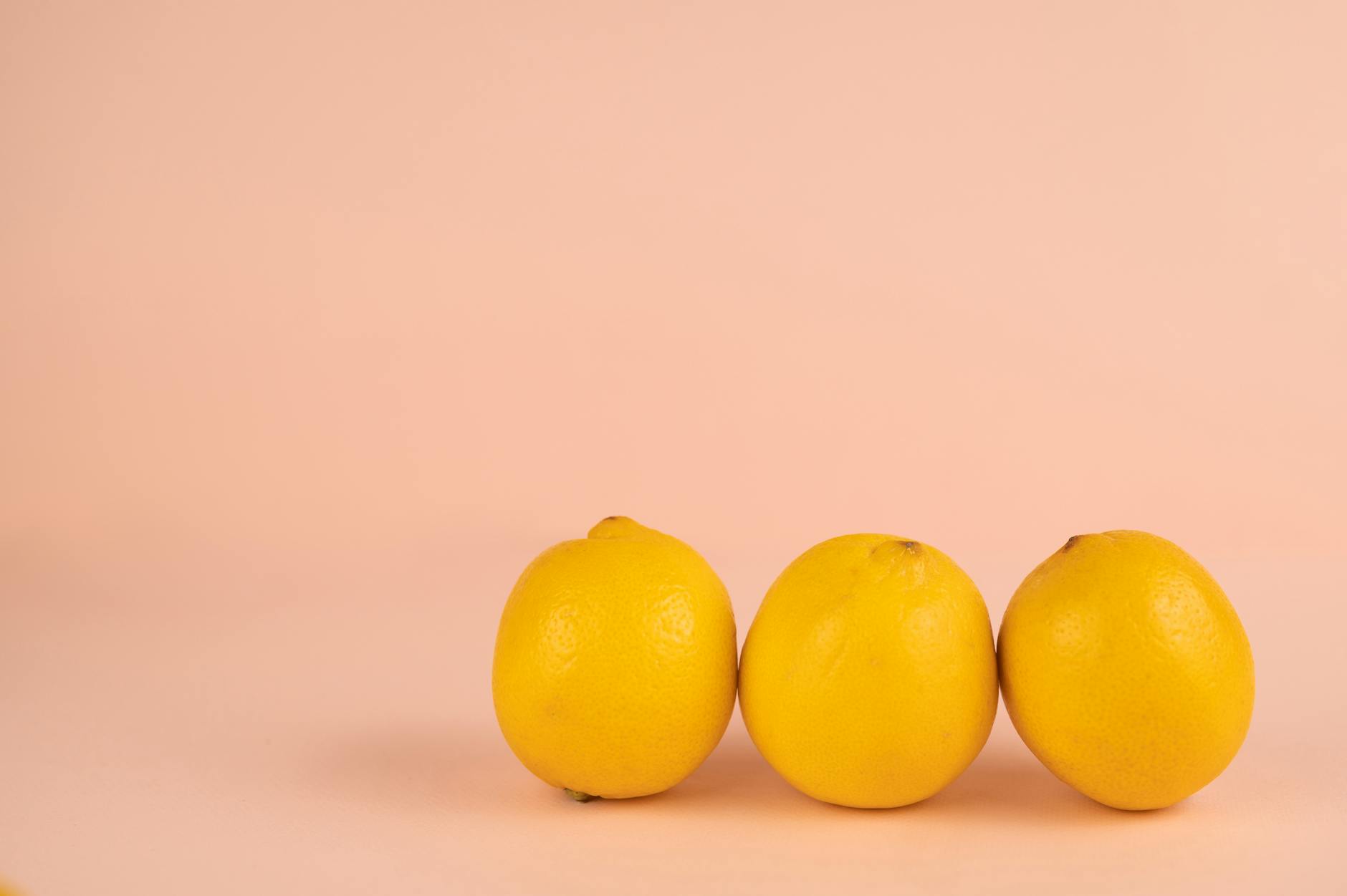 Limões brilhantes e maduros em fundo pastel, representando as mudanças naturais do corpo feminino durante o ciclo menstrual